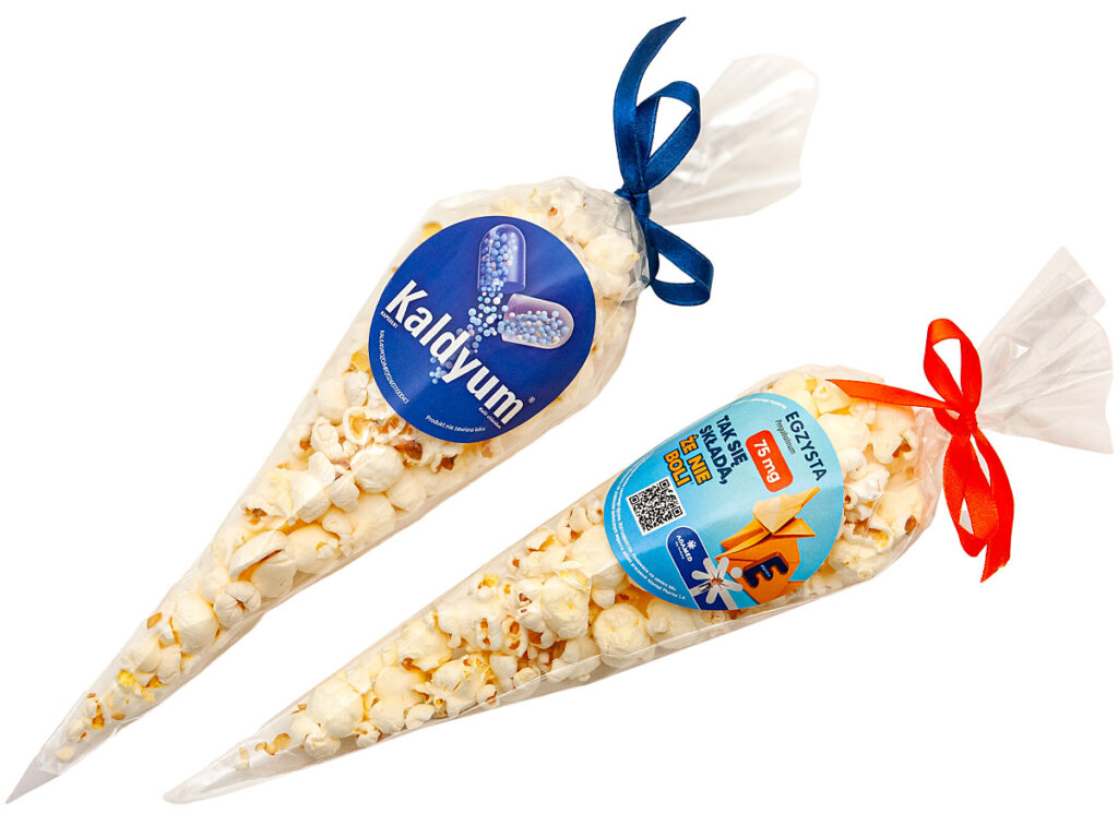 Prażony popcorn solony zapakowany w przezroczysty rożek z firmową naklejką reklamową
